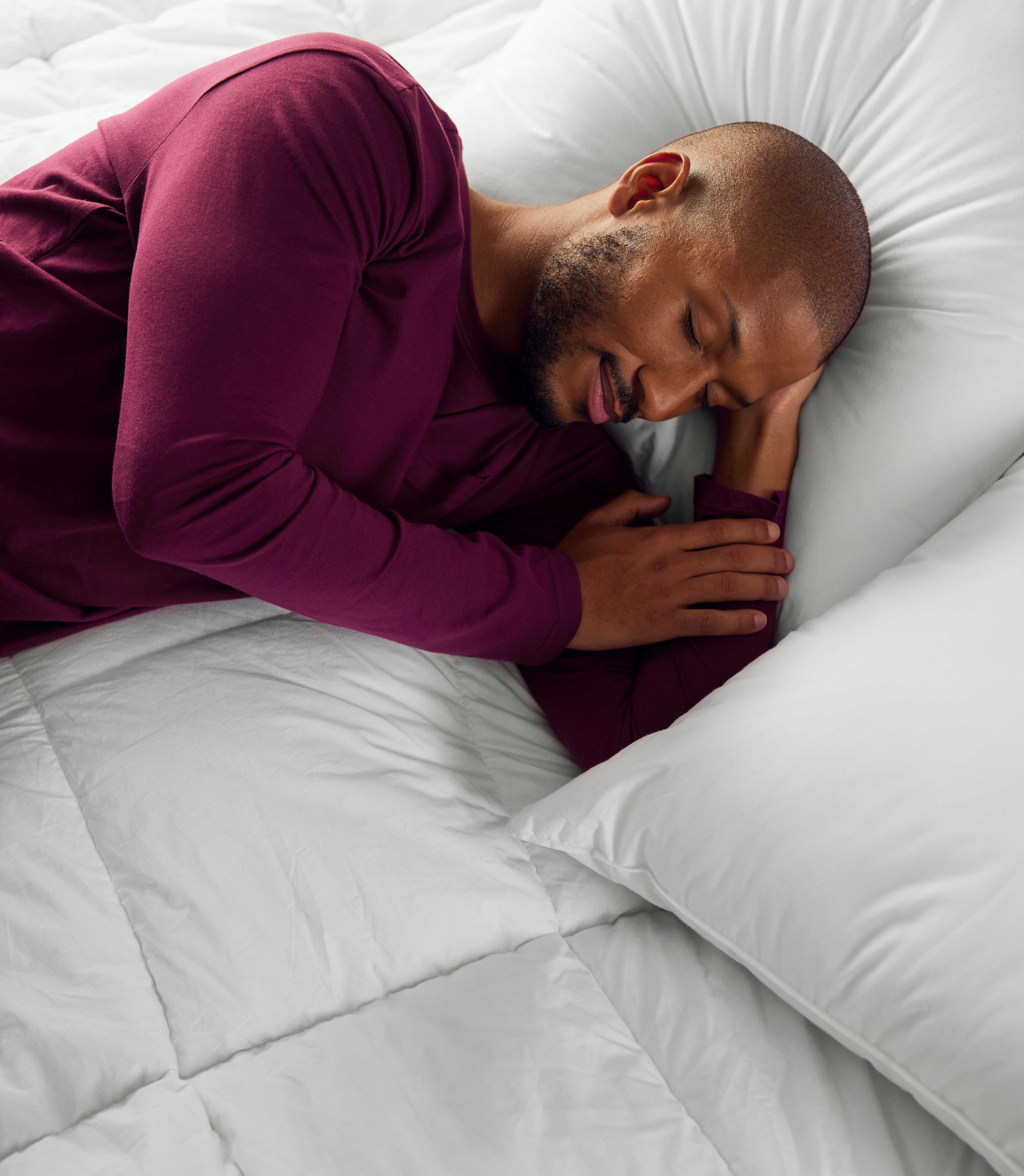 un homme dort dans un lit avec une couette